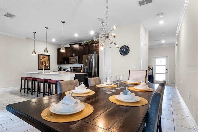 dining room with sink, a notable chandelier, and ornamental molding