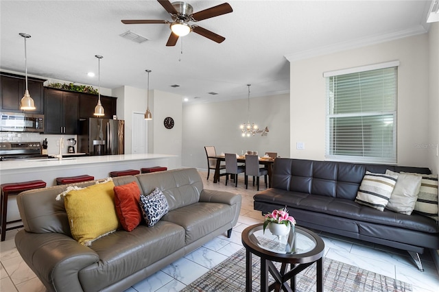 living room with ceiling fan with notable chandelier, crown molding, and sink