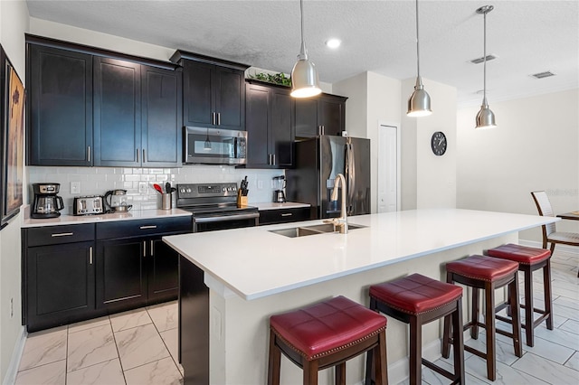 kitchen featuring stainless steel appliances, sink, a kitchen island with sink, tasteful backsplash, and a breakfast bar