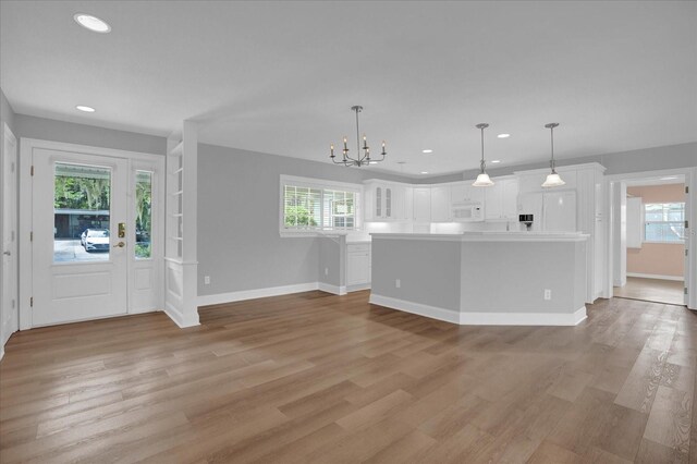 interior space featuring built in features, light hardwood / wood-style flooring, and a notable chandelier