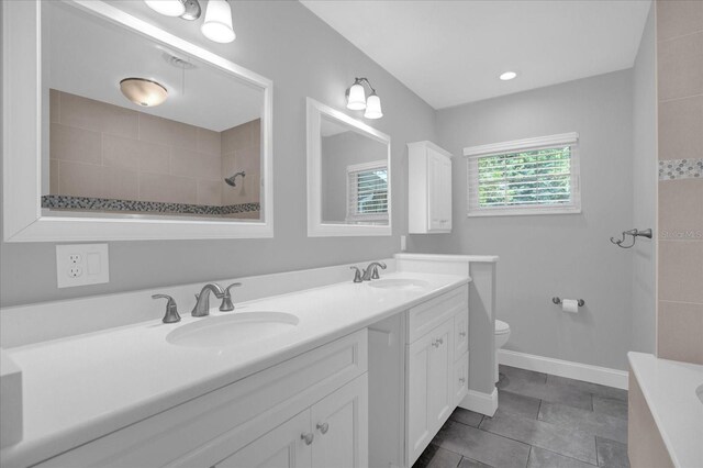 full bath with tiled shower, a sink, toilet, and double vanity