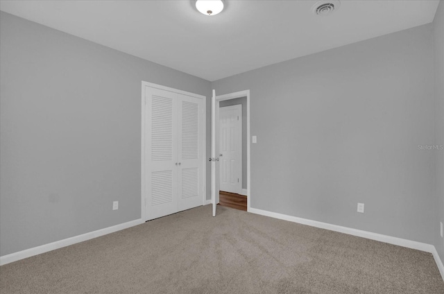 unfurnished bedroom with carpet floors, a closet, visible vents, and baseboards