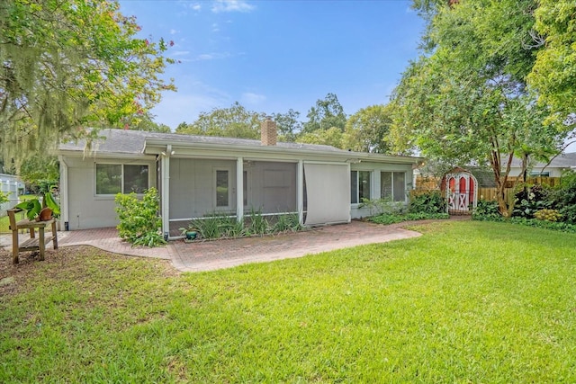 rear view of property with fence, a lawn, a chimney, and a patio