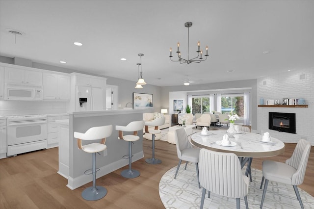 dining space featuring an inviting chandelier, sink, a fireplace, and light hardwood / wood-style flooring