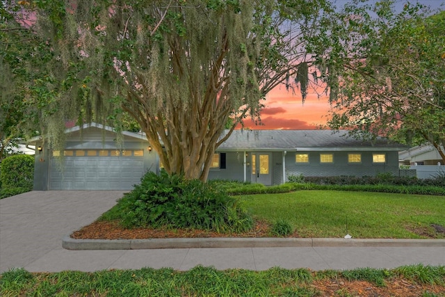 view of front of house with a garage, a yard, brick siding, and concrete driveway