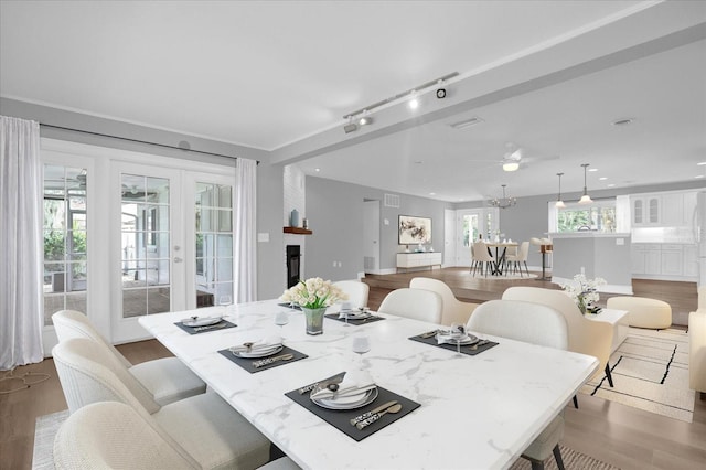 dining area featuring french doors, a fireplace, recessed lighting, rail lighting, and wood finished floors