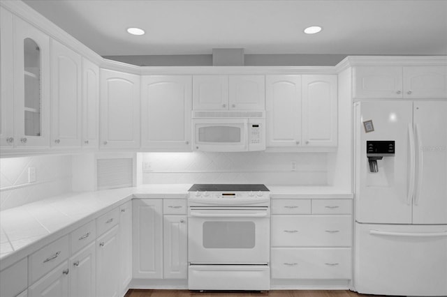 kitchen featuring tile counters, decorative backsplash, glass insert cabinets, white cabinetry, and white appliances