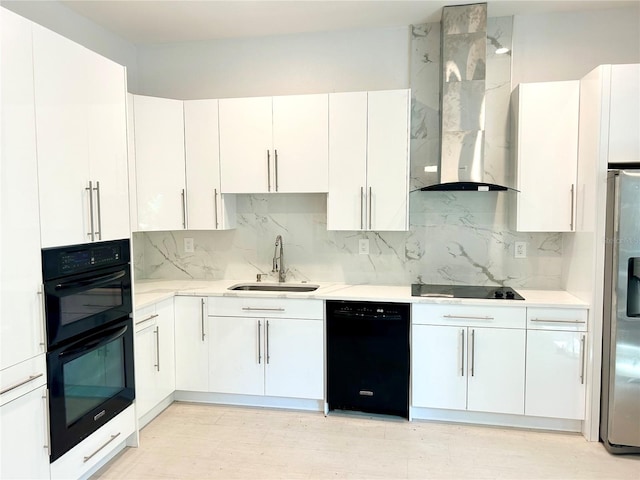 kitchen with black appliances, sink, decorative backsplash, white cabinetry, and wall chimney range hood