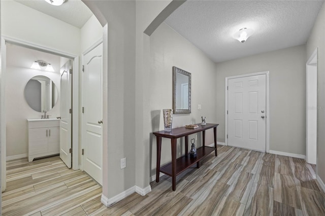 foyer with light hardwood / wood-style floors, sink, and a textured ceiling