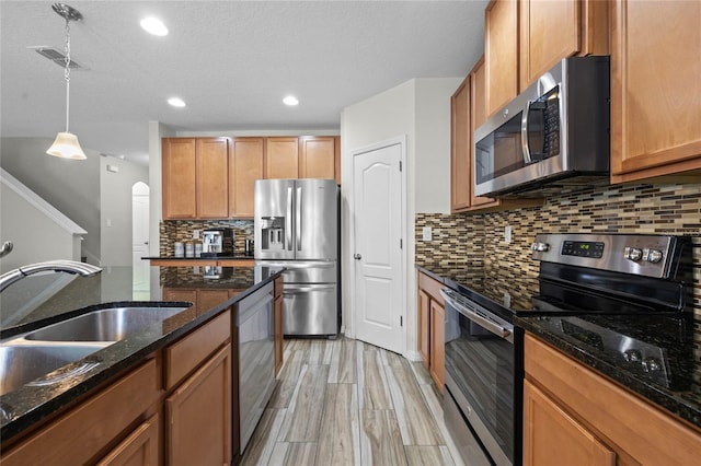 kitchen featuring pendant lighting, sink, a textured ceiling, stainless steel appliances, and decorative backsplash