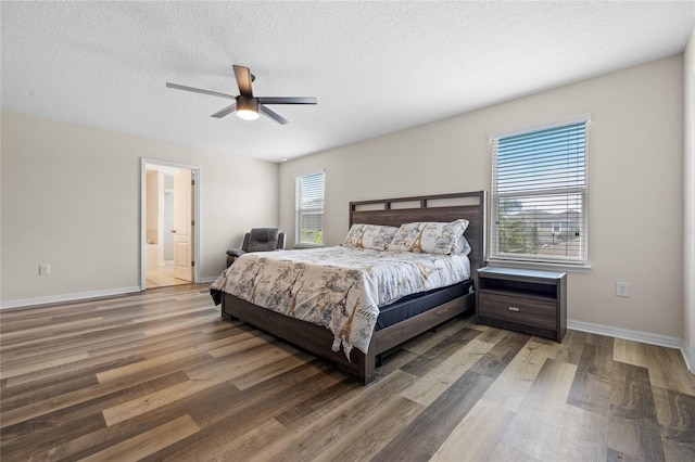 bedroom featuring ceiling fan, ensuite bath, multiple windows, and hardwood / wood-style floors