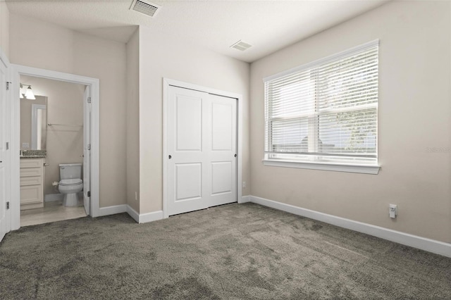 unfurnished bedroom featuring connected bathroom, a closet, and carpet floors