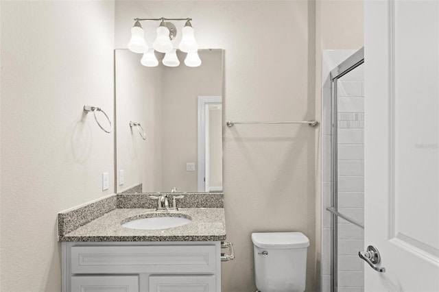 bathroom featuring toilet, a shower with door, and vanity