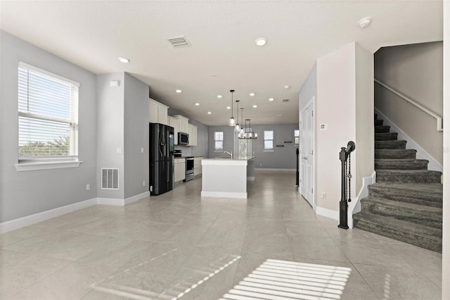 unfurnished living room with a wealth of natural light, an inviting chandelier, and sink