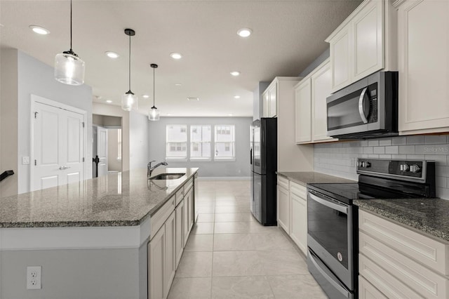 kitchen with pendant lighting, white cabinetry, tasteful backsplash, stainless steel appliances, and a center island with sink