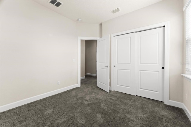 unfurnished bedroom featuring a closet and dark colored carpet