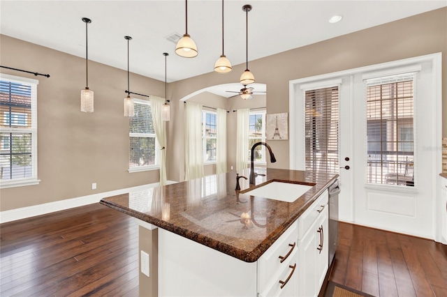 kitchen featuring hanging light fixtures, white cabinetry, sink, a wealth of natural light, and a kitchen island with sink