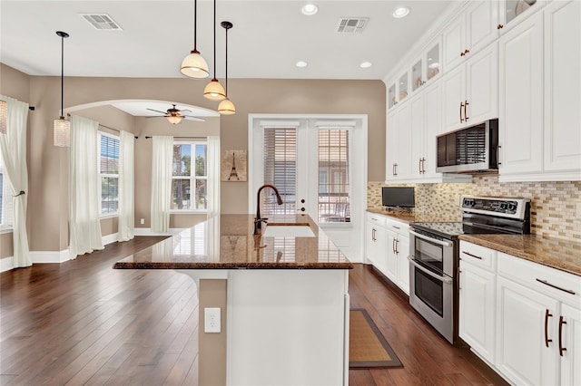 kitchen with appliances with stainless steel finishes, a kitchen island with sink, a breakfast bar, sink, and dark stone counters