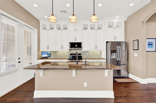 kitchen with appliances with stainless steel finishes, a center island with sink, and a breakfast bar