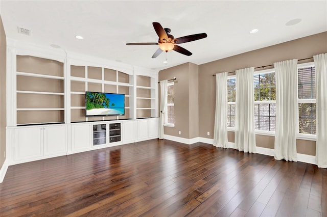 unfurnished living room featuring built in shelves, ceiling fan, and dark hardwood / wood-style floors