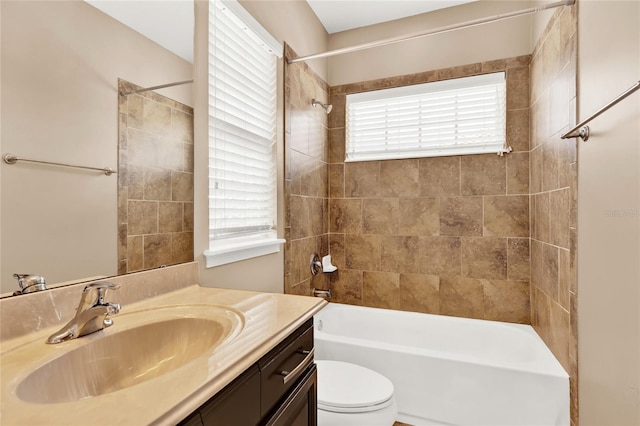 full bathroom featuring tiled shower / bath combo, vanity, toilet, and a healthy amount of sunlight