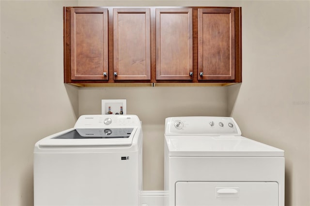 clothes washing area with cabinets and washer and dryer