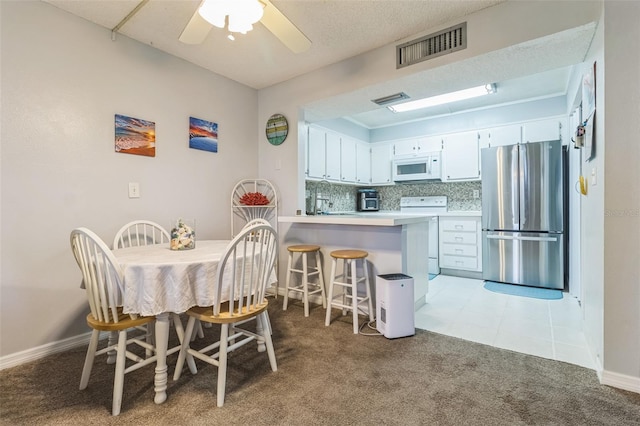 dining room with light carpet, sink, and ceiling fan