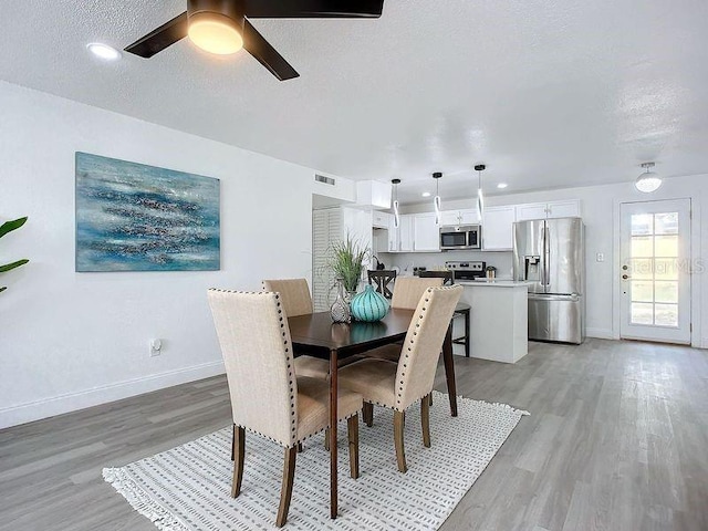 dining space featuring ceiling fan, light hardwood / wood-style floors, and a textured ceiling