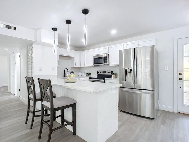 kitchen with white cabinetry, kitchen peninsula, stainless steel appliances, and light hardwood / wood-style floors