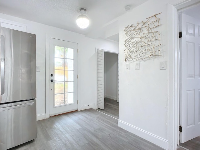 doorway featuring a textured ceiling and light hardwood / wood-style floors