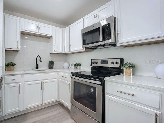 kitchen featuring light hardwood / wood-style flooring, stainless steel appliances, sink, and white cabinetry