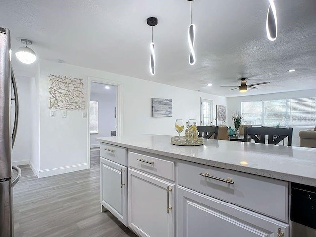 kitchen featuring decorative light fixtures, light hardwood / wood-style floors, stainless steel refrigerator, ceiling fan, and a textured ceiling