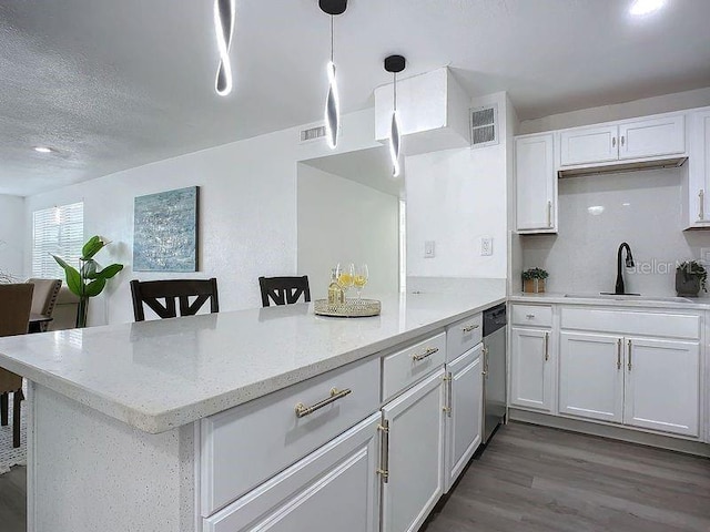 kitchen with white cabinets, decorative light fixtures, light stone counters, kitchen peninsula, and a breakfast bar