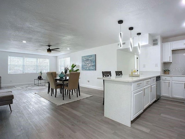 kitchen featuring pendant lighting, hardwood / wood-style floors, kitchen peninsula, ceiling fan, and white cabinets