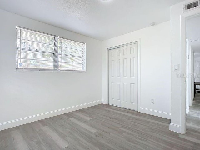 unfurnished bedroom featuring a textured ceiling, hardwood / wood-style flooring, and a closet