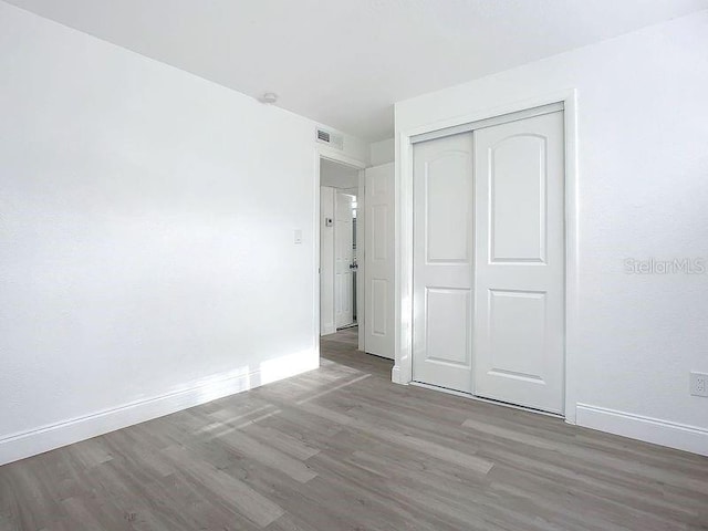 unfurnished bedroom with a closet and hardwood / wood-style flooring