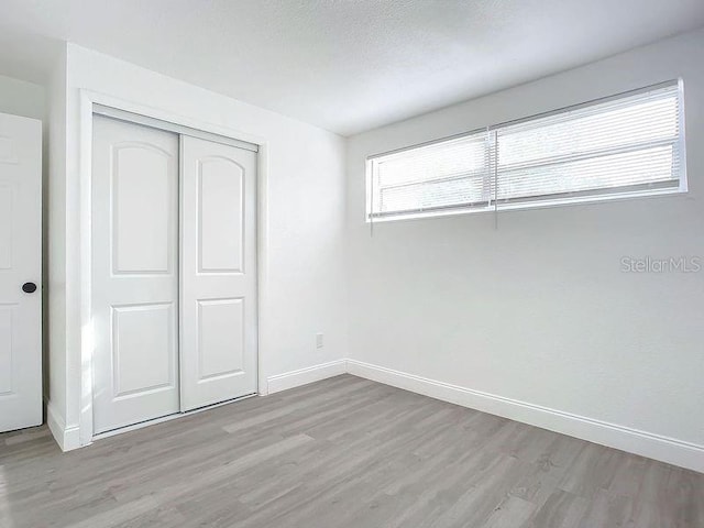 unfurnished bedroom with a closet, hardwood / wood-style flooring, and a textured ceiling