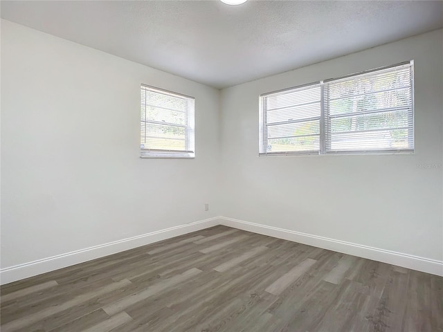 empty room with dark hardwood / wood-style flooring, a textured ceiling, and a healthy amount of sunlight