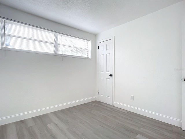 empty room with a textured ceiling and hardwood / wood-style flooring