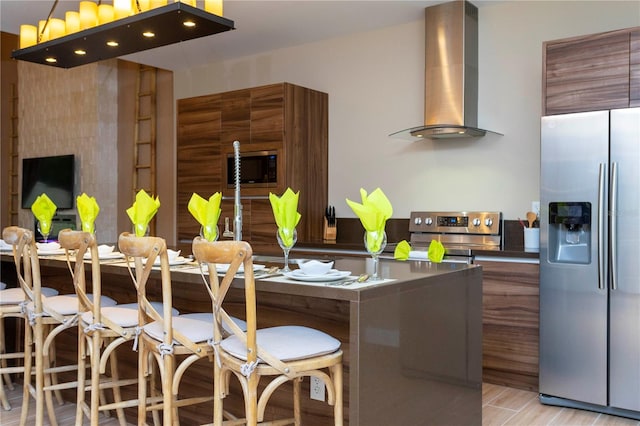 kitchen featuring wall chimney range hood, hardwood / wood-style floors, and appliances with stainless steel finishes