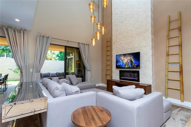 living room featuring plenty of natural light, a towering ceiling, hardwood / wood-style floors, and a fireplace