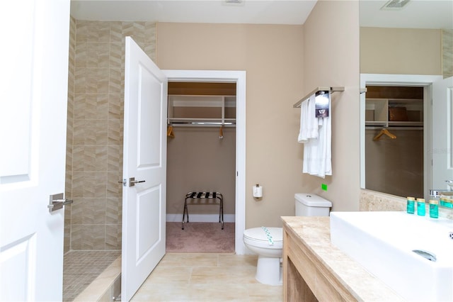 bathroom featuring vanity, toilet, a tile shower, and tile patterned floors