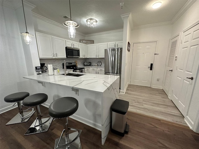 kitchen featuring hanging light fixtures, appliances with stainless steel finishes, dark hardwood / wood-style floors, kitchen peninsula, and tasteful backsplash