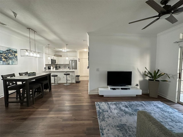 living room featuring ceiling fan with notable chandelier, dark wood-type flooring, ornamental molding, and a textured ceiling