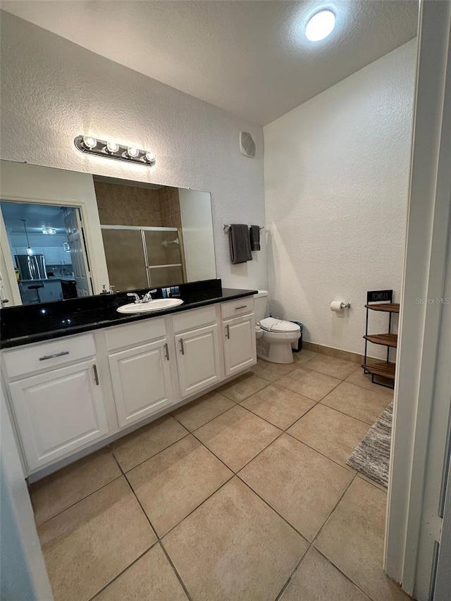 bathroom featuring tile patterned floors, walk in shower, toilet, and vanity