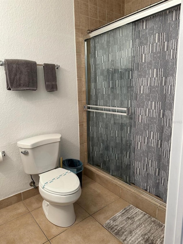 bathroom featuring tile patterned flooring, toilet, and walk in shower