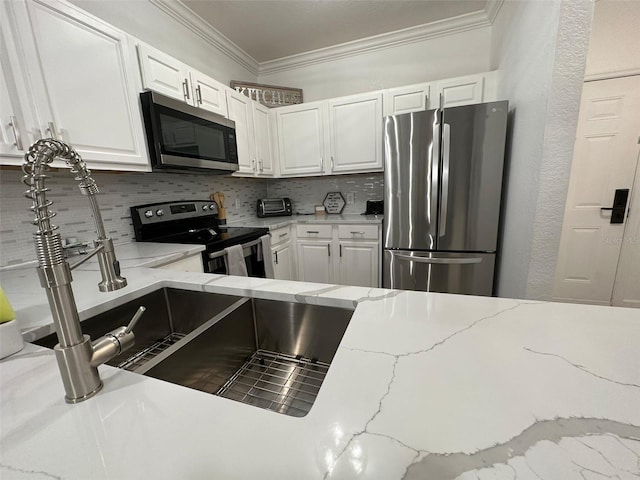 kitchen with appliances with stainless steel finishes, crown molding, decorative backsplash, white cabinetry, and light stone counters