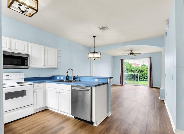 kitchen featuring visible vents, arched walkways, a peninsula, stainless steel appliances, and a sink