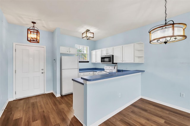 kitchen with a peninsula, white appliances, dark wood-type flooring, white cabinets, and dark countertops