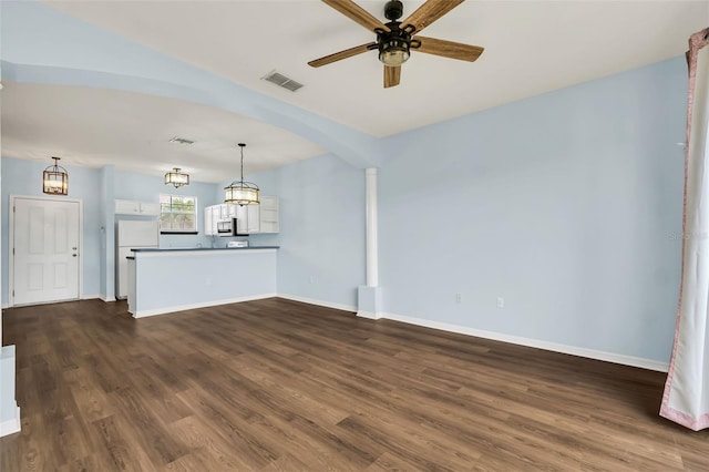 unfurnished living room featuring visible vents, arched walkways, baseboards, dark wood-style floors, and ceiling fan